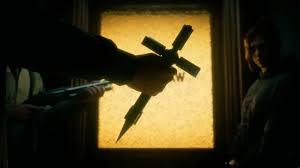 A screenshot from Hunter the Reckoning: Deathwish shows a hunter with a spiked cross approaching a vampire cop's office.